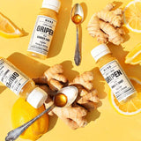 MONO Gripen Shot vor gelben Hintergrund mit Zitronen, Ingwer und Honig