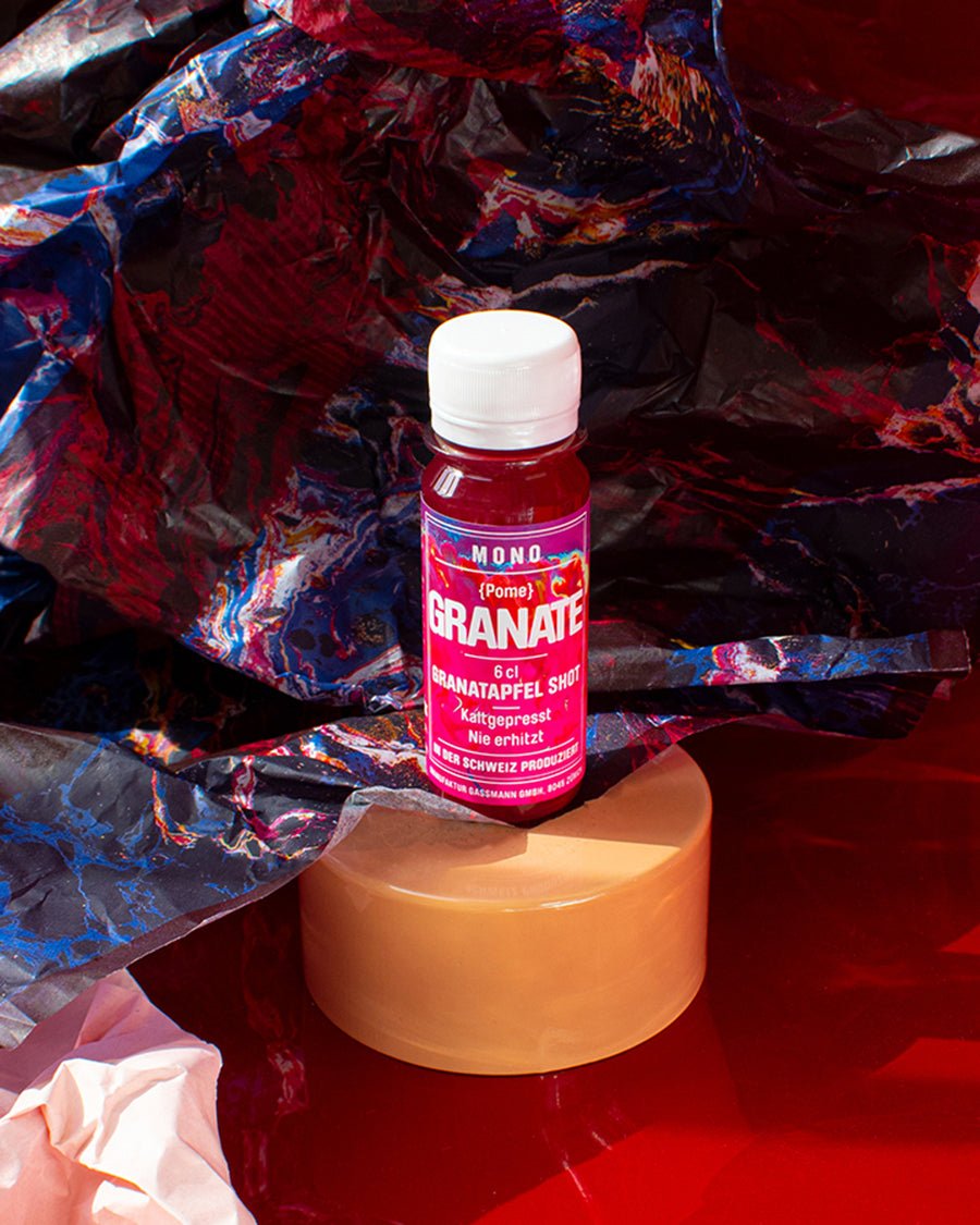 MONO Vitaminshot Granate vor roten Hintergrund 